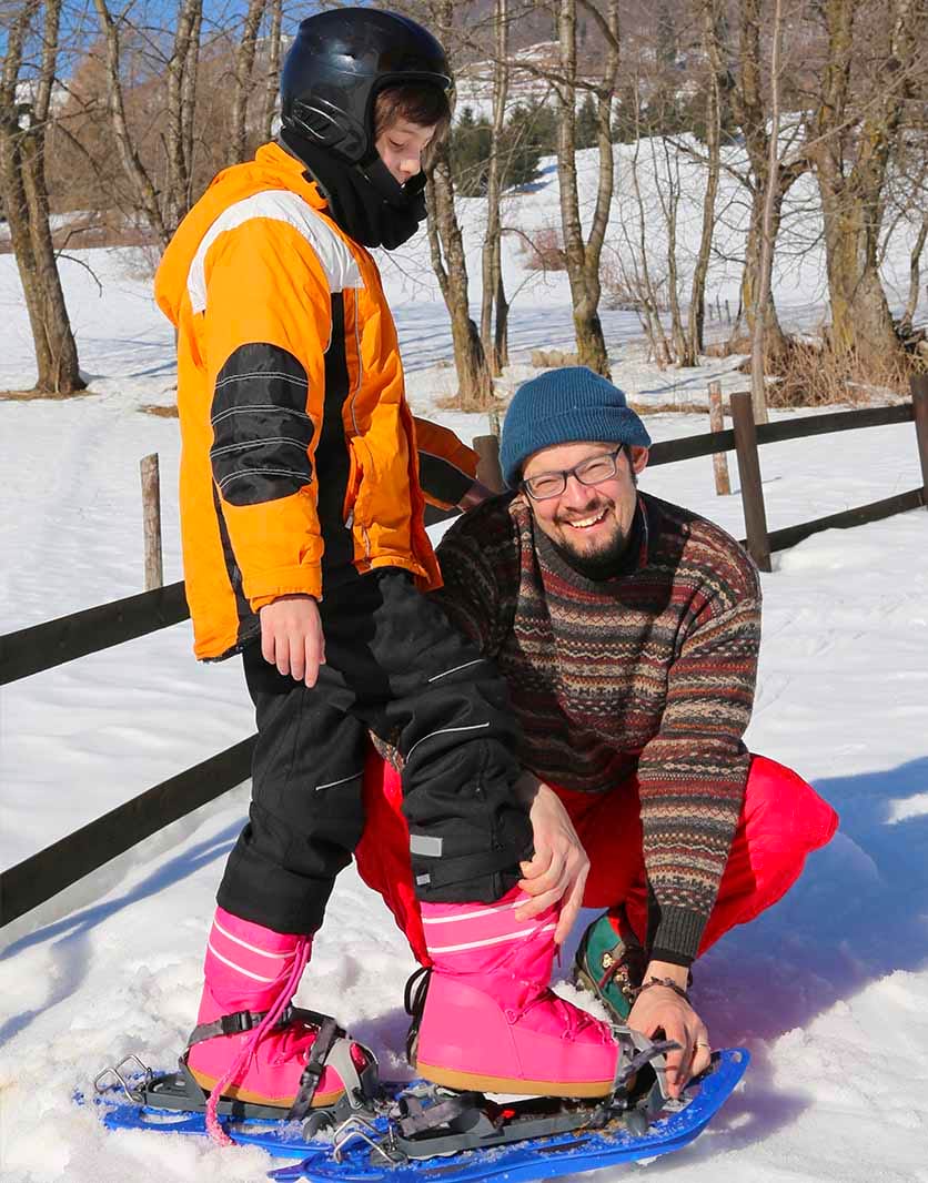 Professeur aidant son élève à mettre ses raquettes à neige en classe de neige