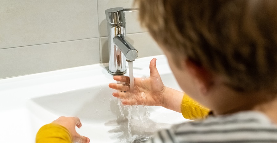 un enfant de dos se lave les mains au lavabo 