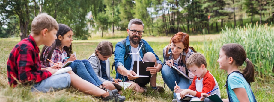 des enfants autour d'un éducateur font une expérience sur le vent dans la nature