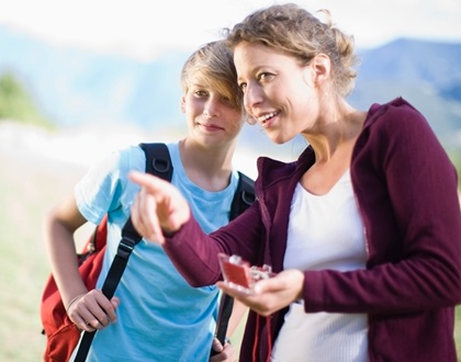 Une animatrice guide un jeune lors d'une parcours aventure avec carte