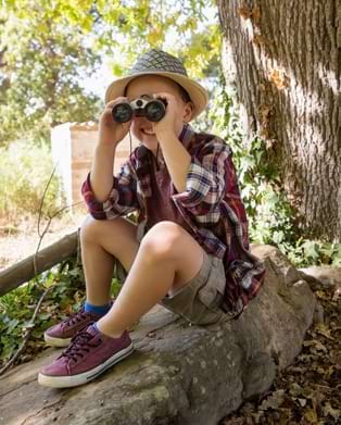 Petit garçon aventurier en train d'observer la nature à travers ses jumelles