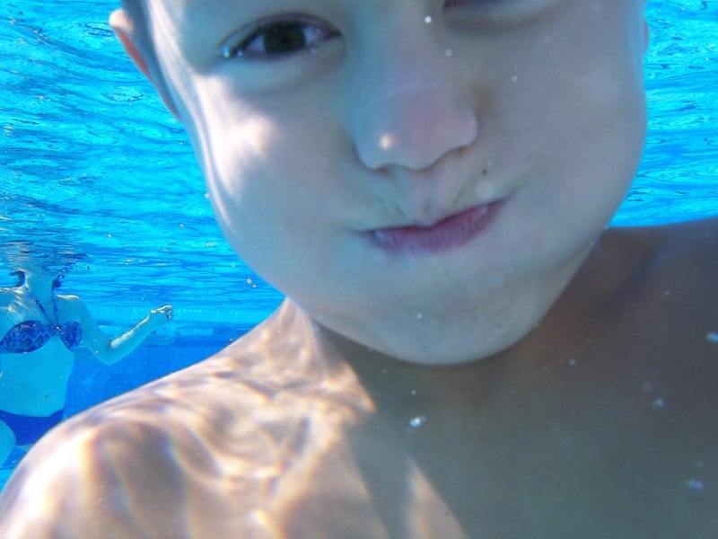 Enfant retenant sa respiration sous l'eau en colo à la piscine
