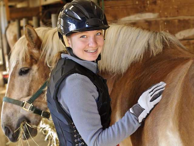 portrait d'une jeune fille prenant soin de son cheval en colo