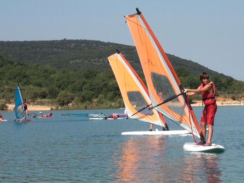 adolescents faisant de la planche à voile en colonie de vacances d'été 