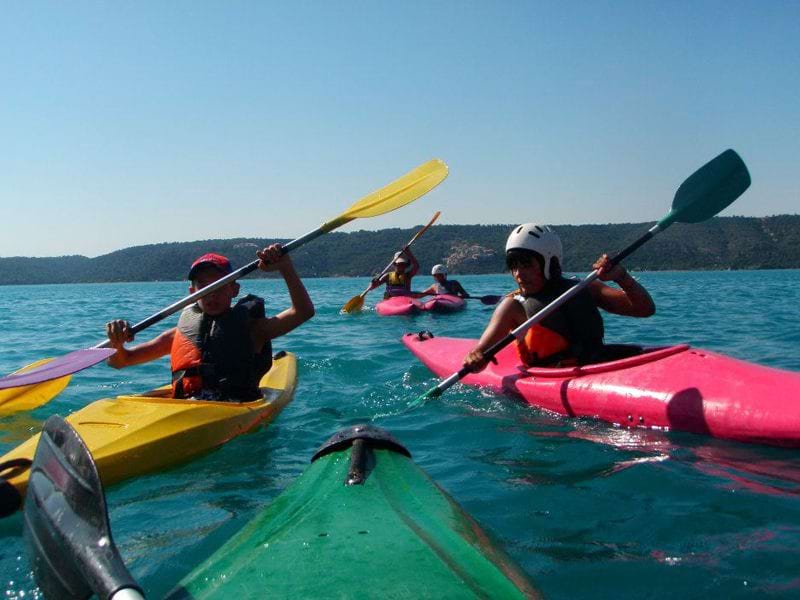 enfants et adolescents faisant du canoe kayak en colonie de vacances d'été