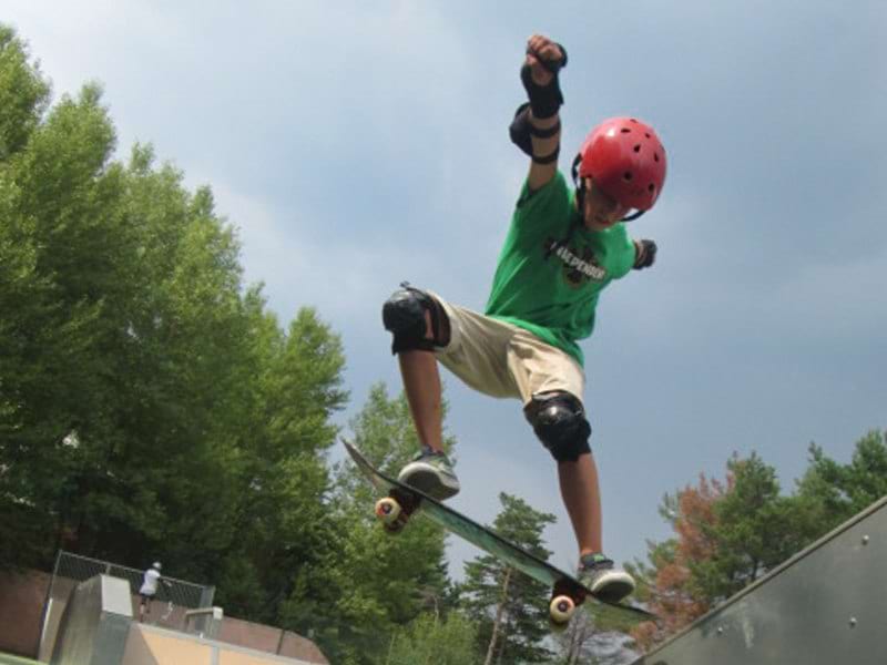 enfant faisant du skateboard freestyle en colonie de vacances d'été