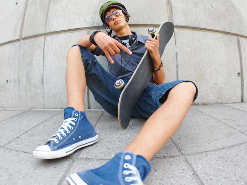 Adolescent assis par terre avec son skateboard en colonie de vacances trottinette