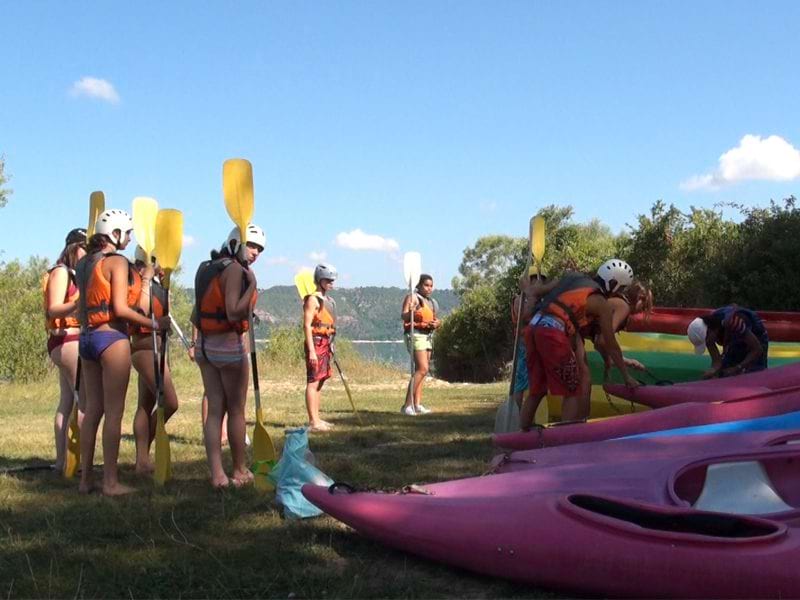 Adolescents s'appretant à faire du canoe kayak en colonie de vacances 