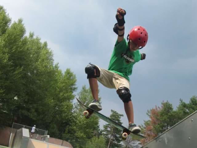 Ado pratiquant le saut en skateboard en colonie de vacances skate cet été