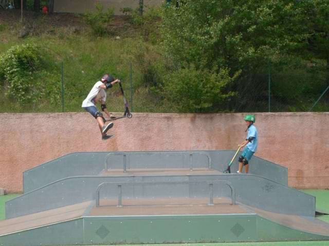 Enfants faisant des sauts en trottinette en colonie de vacances skate