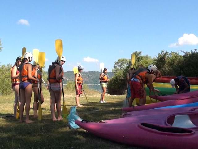 Groupe d'ados et leur pagaie s'appretant à faire du canoe kayak en colonie de vacances