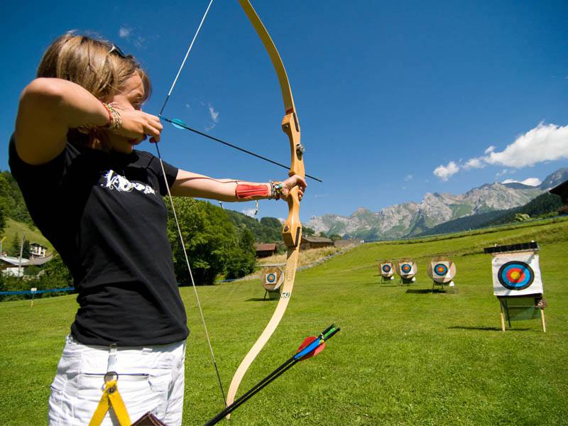 Ados visant une cible avec son arc en colonie de vacances tir à l'arc été