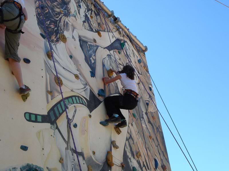 Enfant sur la paroi d'un mur d'escalade en colonie de vacances multisports été