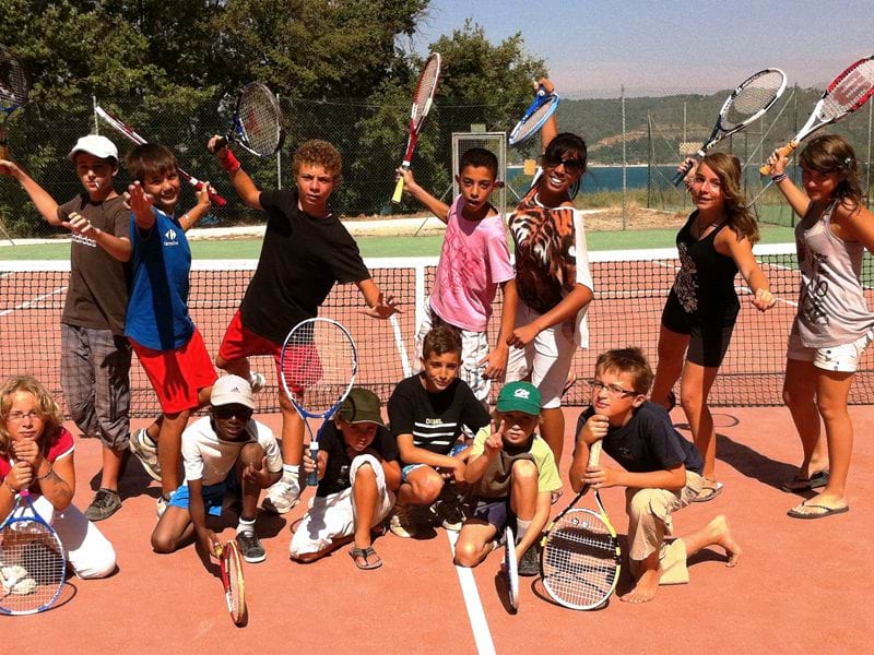 Groupe d'enfants en colonie de vacances tennis sur un court de tennis