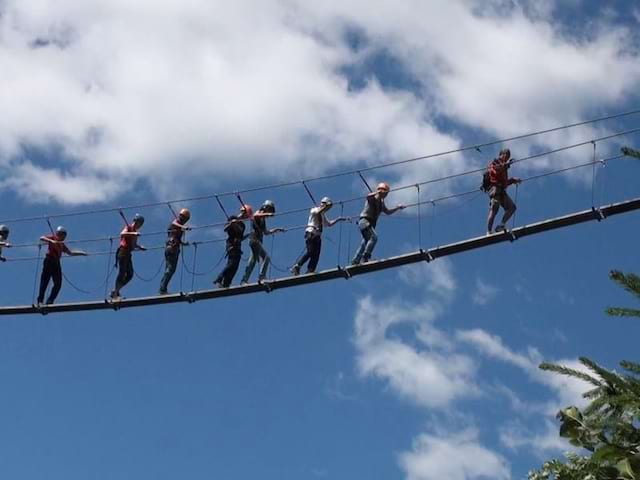 Enfants en colonie de vacances sur un pont de singe évoluant dans les airs 