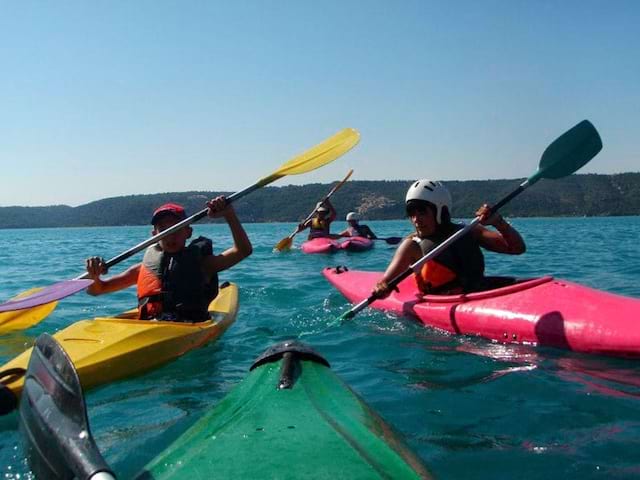 Enfants sur l'eau sur des canoe kayak colorés en colonie de vacances multiacitivités dans le verdon été 