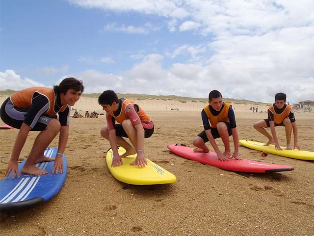 Groupe d'ados sur la plage apprenant à tenir en équilibre sur la planche de surf 