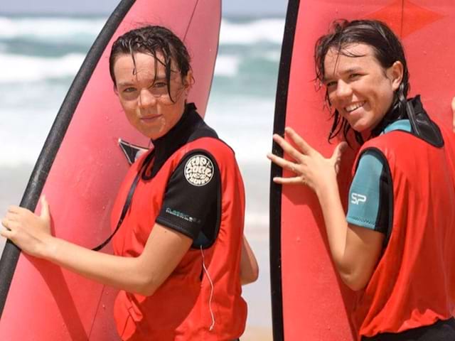 Deux adolescents avec leur planche de surf en colonie de vacances à l'océan 