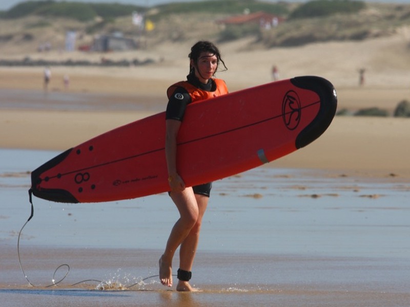 Adolescente portant sa planche de surf en colonie