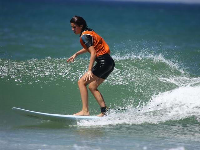 Adolescente faisant du surf à l'océan en colonie de vacances d'été