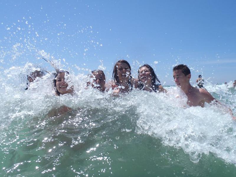 Groupe d'enfants et ados se baignant à l'océan en colonie de vacances été