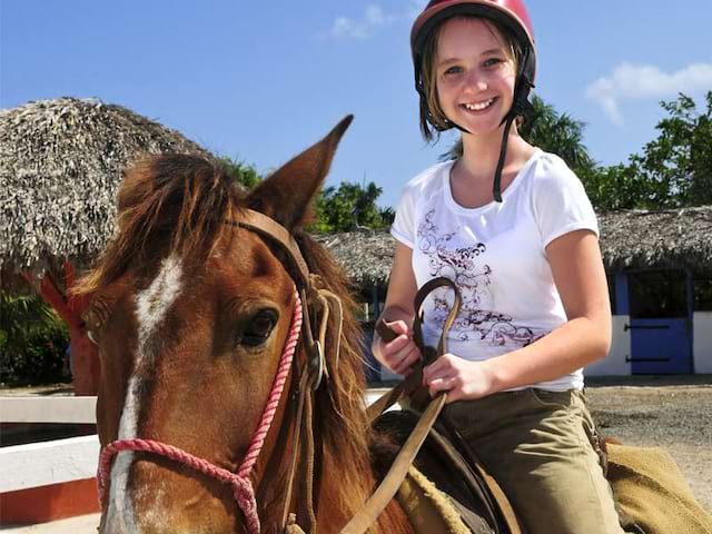 Adolescente de 15 ans faisant de l'équitation en colonie de vacances à la montagne cet été