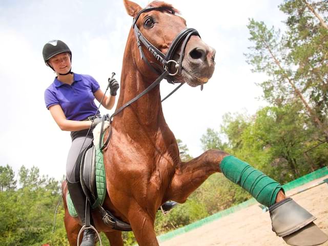 Adolescente faisant de l'équitation en colonie de vacances à la montagne cet été 