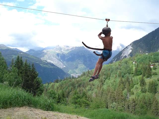 Adolescent faisant de la tyrolienne en montagne cet été en colo 