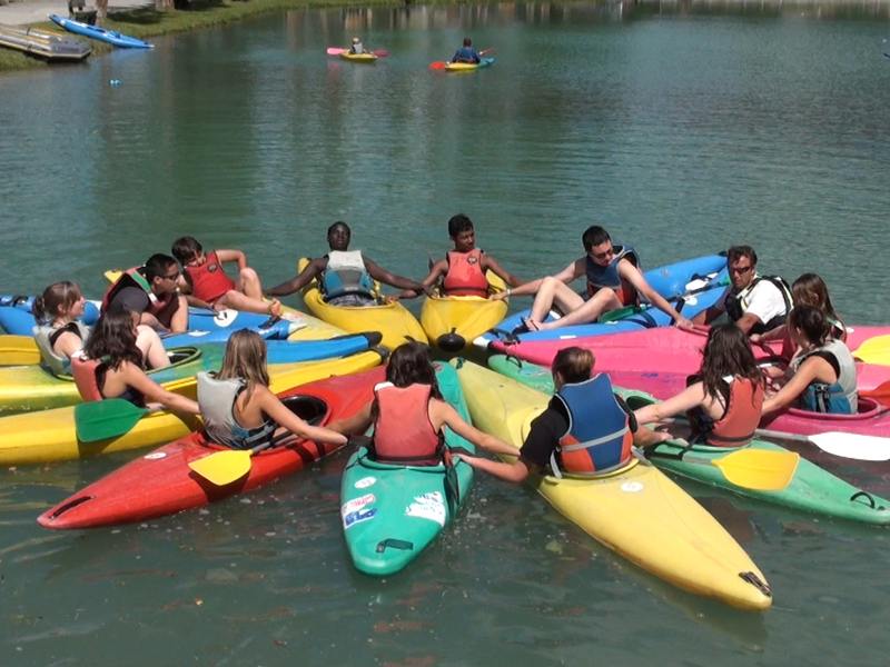 Enfants et ados faisant du canoe kayak en colonie de vacances à la montagne cet été