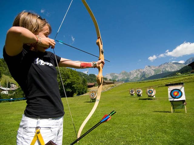 Enfant visant els cibles de tir à l'arc en colonie de vacances à la montagne à Courchevel