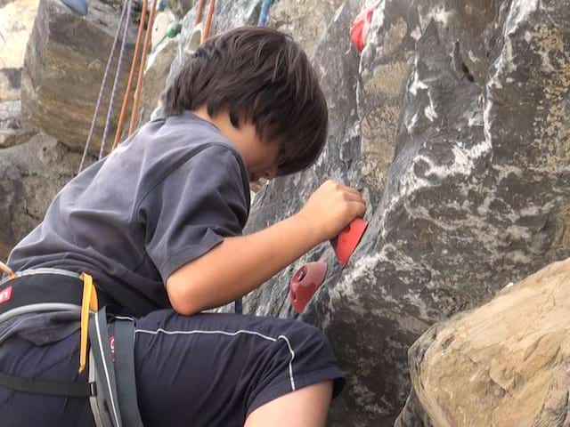 Enfant faisant de l'escalade en colo à la montagne