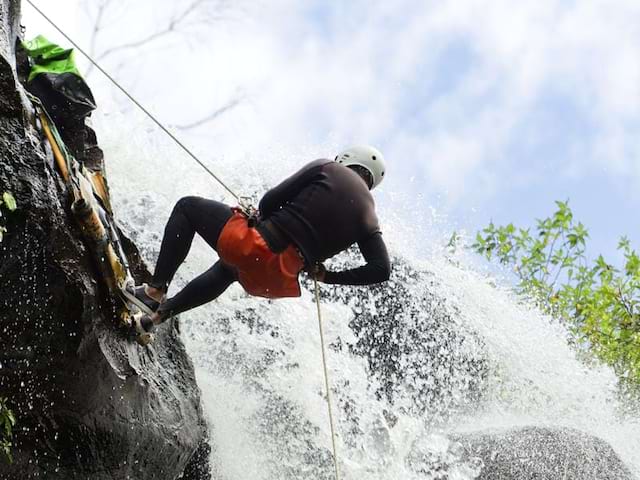 Ado descendant la cascade en canyoning à la montagne l'été