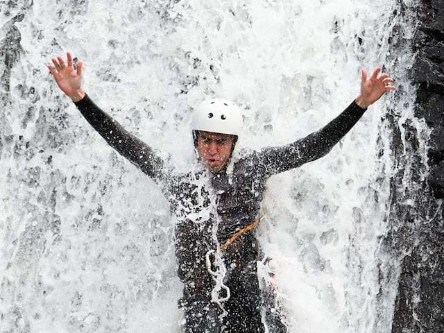 Enfant sous la cascade en canyoning été montagne