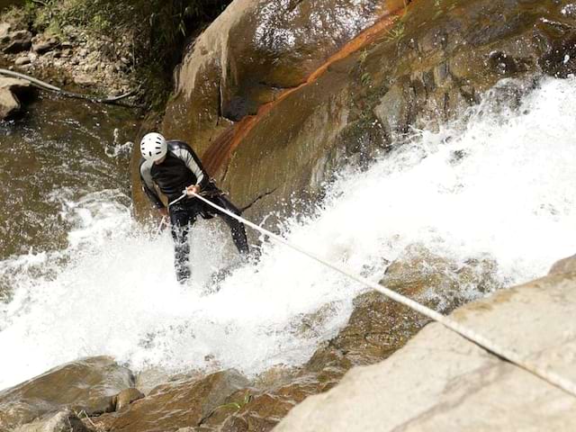 Enfant descendant en canyoning en colonie de vacances d'été montagne