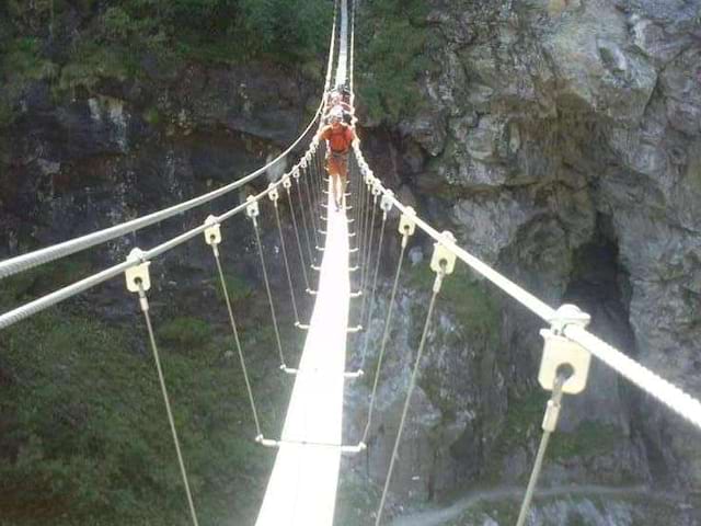 Ado sur un pont en via ferrata à la montagne en colo 