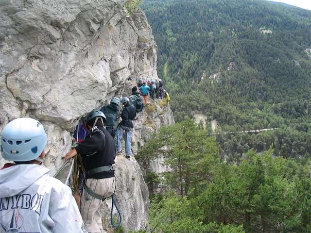 Groupe d'ados et enfants faisant de la via ferrata en colo