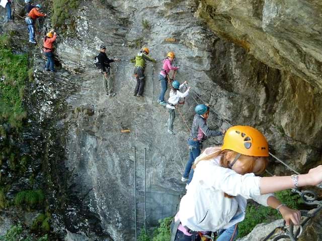 Groupe d'adolescents pratiquant la via ferrata en colonie de vacances d'été à Courchevel