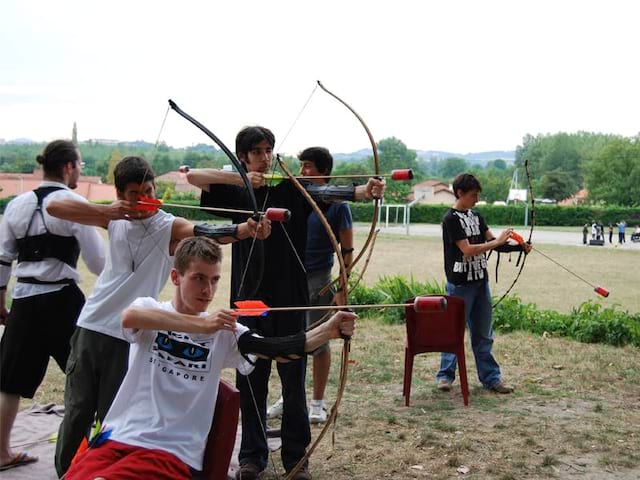 Enfants et ados apprenant à faire du tir à l'arc en colonie de vacances d'été