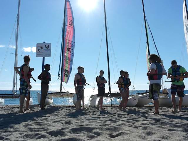 groupe d'ados en bord de mer apprenant à faire du catamaran en colo