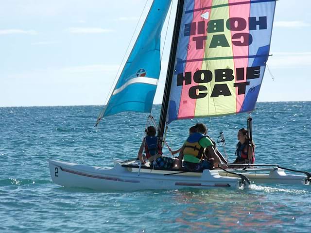 groupe d'ados faisant du catamaran cet été en colonie de vacances a la mer