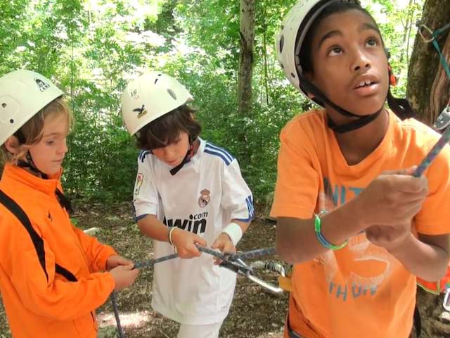 Préadolescents pratiquant la descente en rappel en colonie de vacances d'été