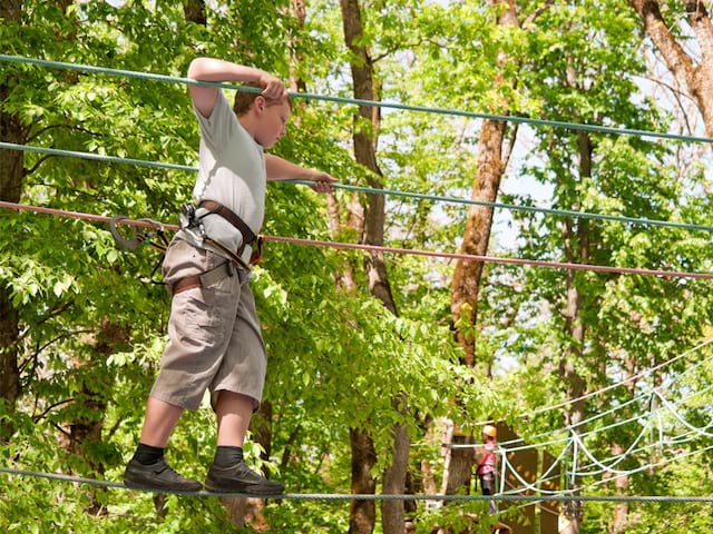 Enfant faisant de l'accrobranche en colonie de vacances multi activités été