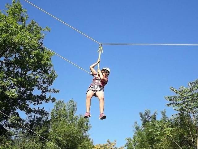 Enfant faisant de la tyrolienne en colo cet été