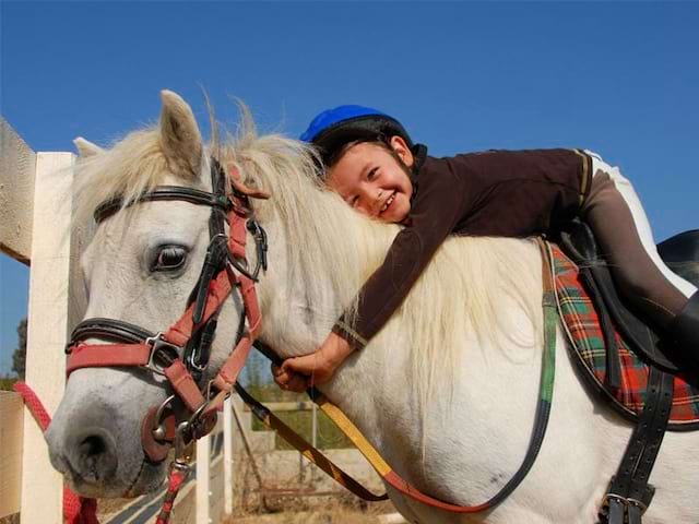 Fillette faisant un calin à son poney en colonie de vacances d'été