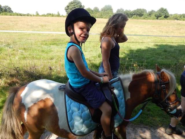 Enfant en balade à dos de poney avec son animatrice de colonie de vacances