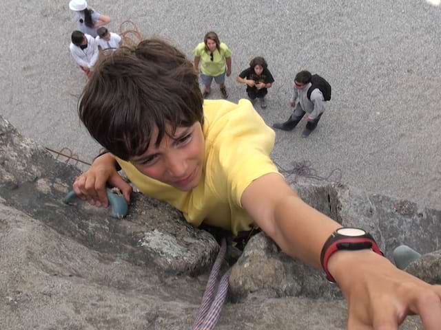 Jeune garçon grimpant sur le mur d'escalade en colonie de vacances été