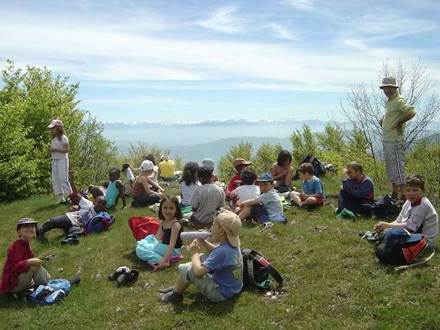 Groupe d'enfants assis dans l'herbe en pic nic en colonie de vacances été