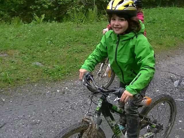 Jeune garçon heureux de faire du vélo à la campagne en colonie de vacances