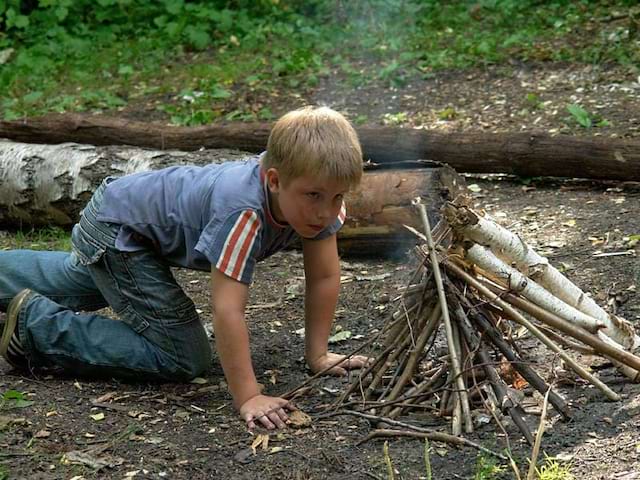 Garçonnet apprenant à faire du feu en colonie de vacances étér