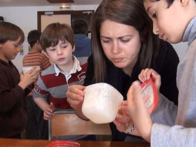 Animatrice de colonie de vacances montrant comment faire du fromage aux enfants en colo été